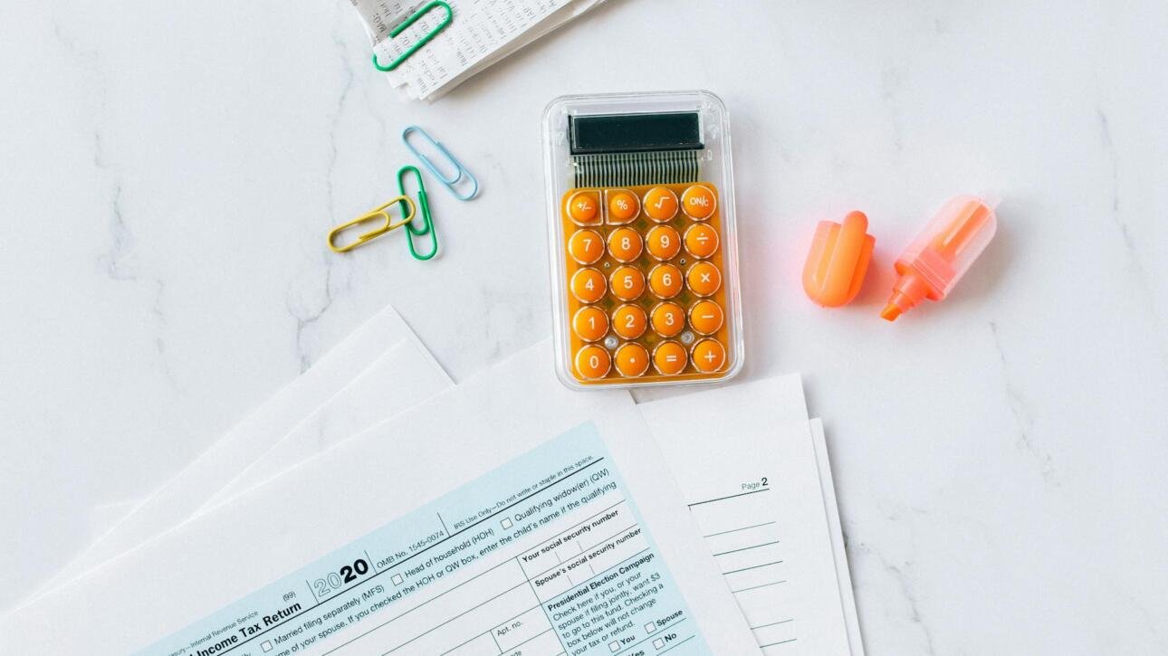 Desk overhead view with tax documents, calculator, and pen illustrating onlyfans taxes for content creators